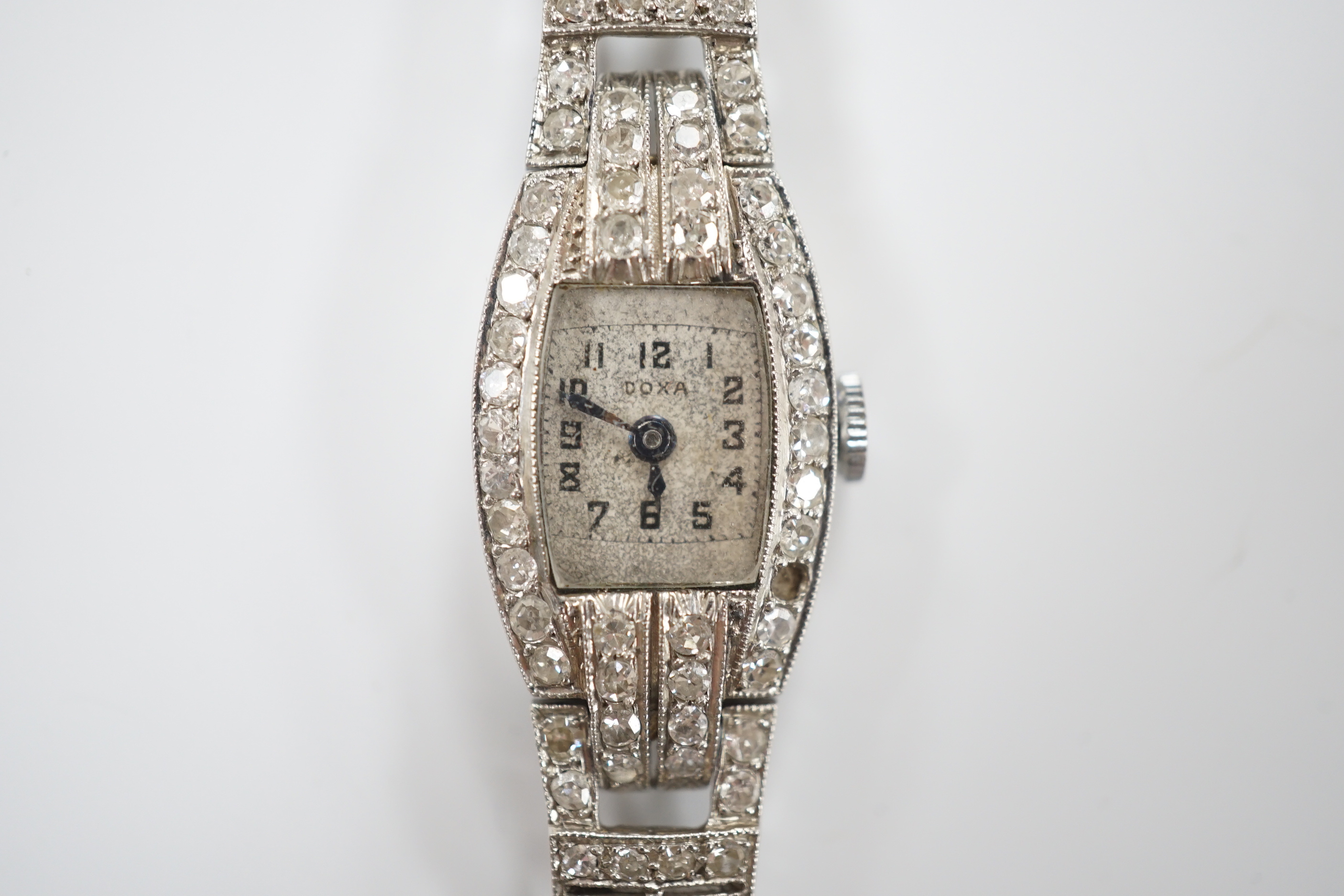 A lady's 1930's/1940's French white metal (platinum mark) and diamond cluster set manual wind cocktail watch, on a twin fabric strap, with metal clasp.